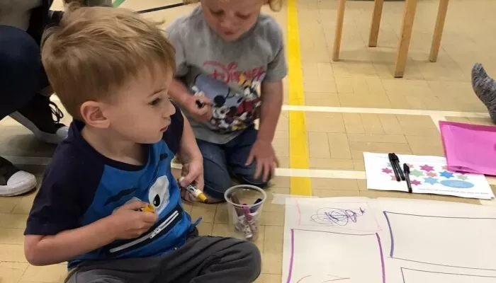 Children drawing on large pieces of paper on the floor